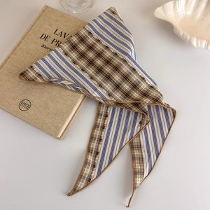 Detail of vintage plaid and striped silk scarf on white tray with antique books
