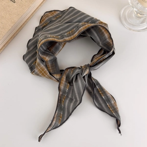 Detailed view of grey and ochre plaid cotton headscarf tied in a knot on a white desk