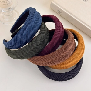 Detail showing various colors of ribbed knit thick sponge headbands in a layered display