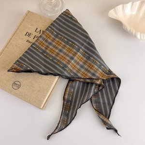 Detail of grey striped and brown checkered silk scarf with fringe on vintage book