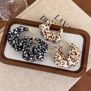 Exaggerated leopard print fabric scrunchie hoop earrings with gold metal pin closures