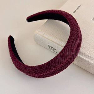 Macro detail of wine red knitted headband showing thick textured fabric and black lining