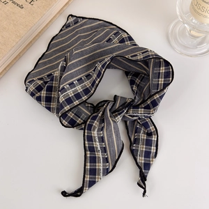 Detail view of navy plaid and taupe striped scarf with fine black stitching on edges