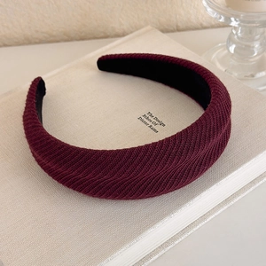 Detailed view of burgundy knitted sponge headband with textured vertical ribbing pattern