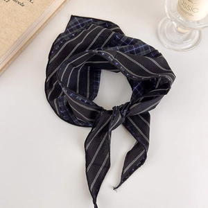 Detail of blue plaid and black striped silk scarf with elegant knotting on a retro table