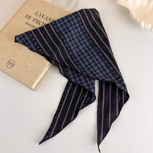 Detail of vintage navy blue plaid scarf with raw edges on white surface