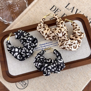Close-up of fabric leopard print scrunchie hoop earrings on a vintage linen tray