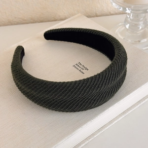 Close-up of deep green knitted sponge headband with textured fabric on a book