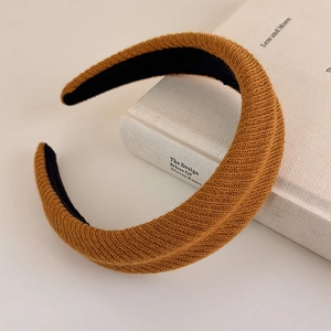 Detail of a brown ribbed knit thick headband resting on a book for a vintage aesthetic