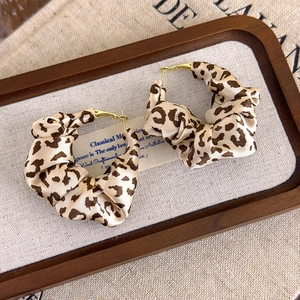 Detail of leopard print fabric hoop earrings with elegant silk pleated texture