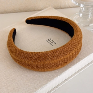 Close-up of ginger yellow knitted headband with thick texture on a white book