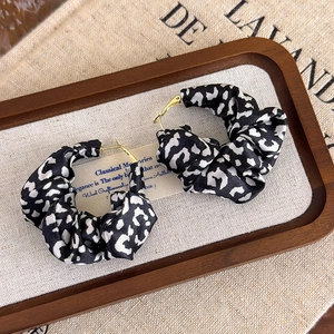 Detailed view of large leopard print fabric hoop earrings on a vintage display tray