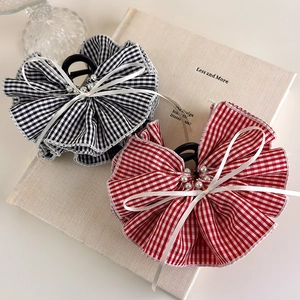 Detail of red and black plaid hair claw clips with pearls on a decorative book