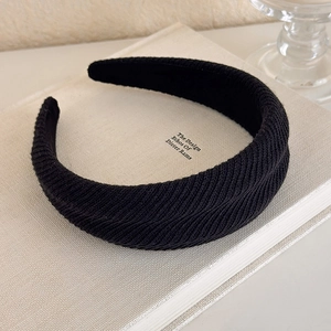 Close-up of a black padded headband featuring a textured knit fabric on a minimalist book