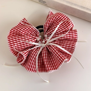 Macro detail of red gingham fabric hair claw clip with faux pearl and satin ribbon accent