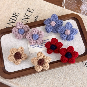 Handmade crochet yarn flower hair pins in purple, blue, yellow and red on wood tray