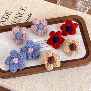 Handmade crochet flower earrings in multiple colors on a rustic wooden tray display