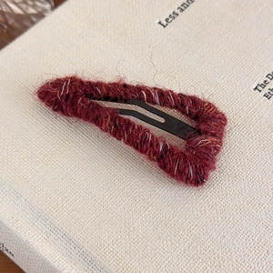 Close-up of wine red yarn-wrapped knit hair clip with yellow and white fiber details