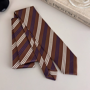 Detail of a brown striped necktie with satin finish on a minimalist desk layout