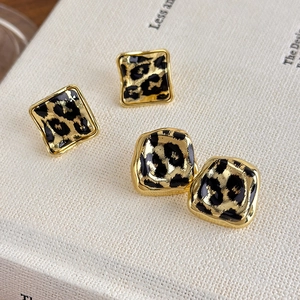 Elegant vintage leopard print geometric earrings with gold textured frames on a book