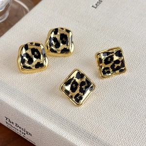 Detail shot of vintage leopard print geometric earrings with gold trim on a book
