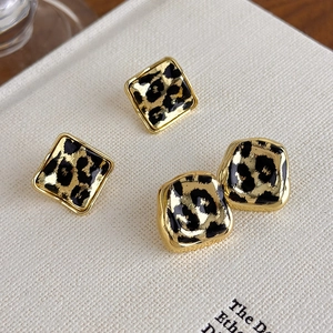 Close-up of leopard print stud earrings in golden square and irregular geometric frames