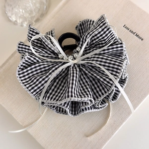 Detail of elegant black and white checkered fabric hair claw with a bow and faux pearls