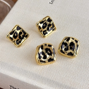 Detailed view of leopard print geometric earrings with gold alloy frame on a white book