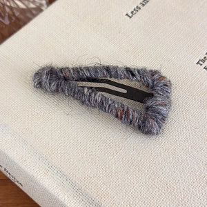 Close-up of triangle wool yarn wrapped metal BB hair clip with textured grey fiber detail