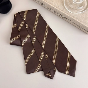 Detail of dark brown striped tie with silk-like satin texture and elegant gold patterns