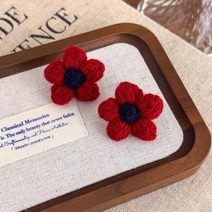 Detailed macro view of handmade red crochet flower earrings on a rustic linen background
