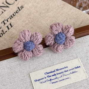 Close-up of handmade crochet flower earrings in lavender and blue yarn textures