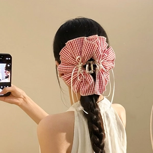 Red and white checkered bow hair claw with pearls worn on dark braided hair