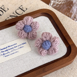 Detailed knit texture of handmade purple and pink crochet flower earrings on a tray