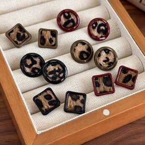 Gros plan de boucles d'oreilles léopard géométriques carrées et rondes sur du velours