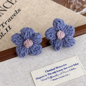 Close-up of handmade knit flower earrings with grey-blue wool yarn and pink center