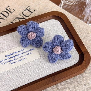 Detailed macro view of handmade purple crochet flower earrings with soft yarn texture