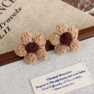Close-up of handmade crochet flower earrings featuring brown petals and knit textures
