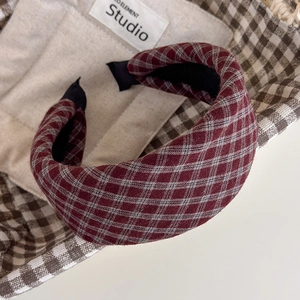 Close-up of padded sponge headband with red and white plaid fabric on a textured background