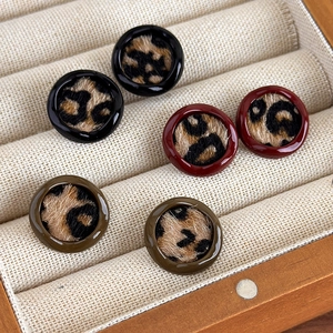 Vue macro de boucles d'oreilles léopard rondes en noir, rouge foncé et velours vert