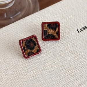 Détail de boucles d'oreilles carrées rouge foncé à motif léopard sur papier
