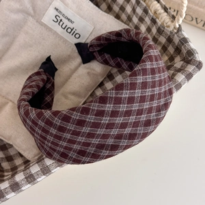 Detail of vintage red-brown plaid padded headband on a beige fabric background