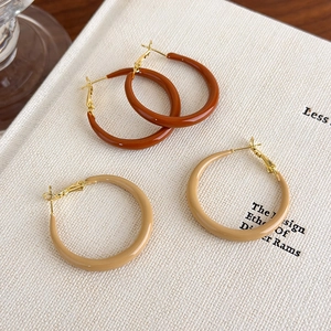 Retro caramel brown and beige hoop earrings with glossy finish on aesthetic book background