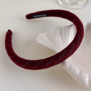 Detail of burgundy knit headband with handmade label and blue diagonal stripe texture