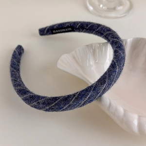 Detail of handmade dark blue knit plaid headband on a white decorative shell plate