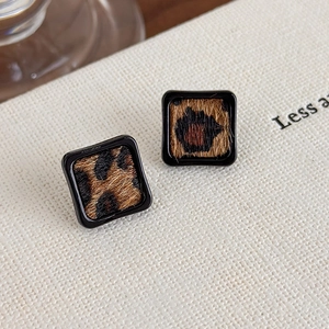 Gros plan de boucles d'oreilles carrées léopard avec cadre noir poli sur fond blanc
