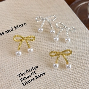 Elegant bow-knot pearl stud earrings set in gold and silver finish with textured metal