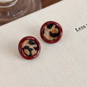 Gros plan de boucles d'oreilles rondes vintage en émail rouge et fausse fourrure léopard