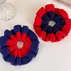 Detail of red and blue knitted hair scrunchies with thick wool texture and contrast stitching