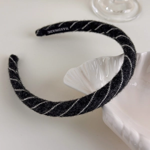 Detailed close-up of a handmade black and white striped knitted fabric headband on a tray